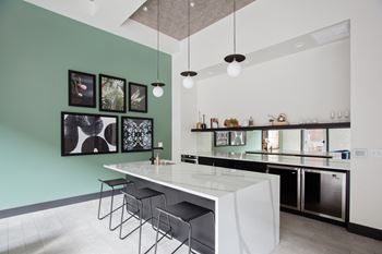 a kitchen with a white counter top and a bar with black stools